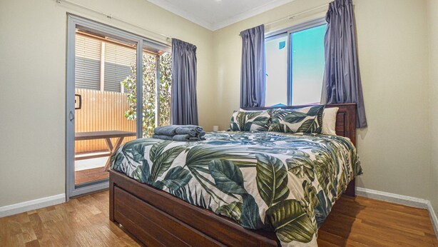 A bedroom with a bed, a sliding glass door to a balcony, and a view of the outside. - Marvellous McKay 3x2 Close to CBD (Port Hedland)