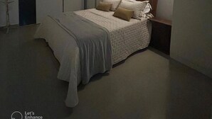 Une chambre à coucher comprenant un lit, une table de chevet et un appareil de climatisation fixé au mur.