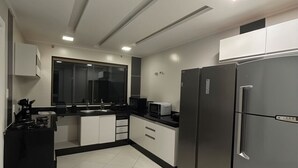 Une cuisine moderne avec un plan de travail noir, des armoires blanches et un réfrigérateur en acier inoxydable.