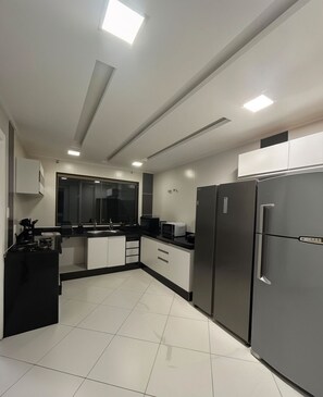 A modern kitchen with a black countertop, white cabinets, and a stainless steel refrigerator.