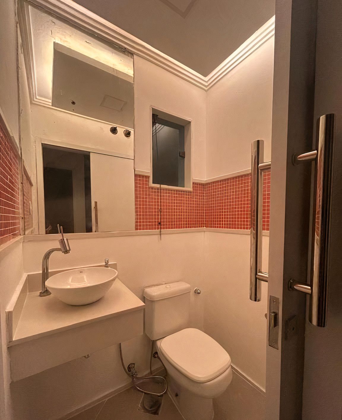 A bathroom with a white sink, toilet, and a red-tiled wall.