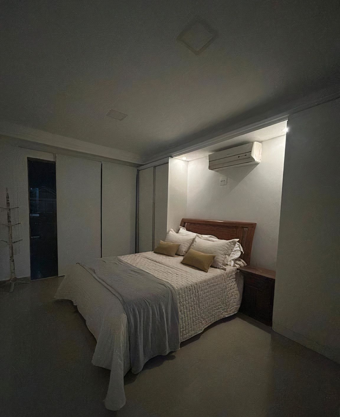 Une chambre à coucher comprenant un lit, une table de chevet et un appareil de climatisation fixé au mur.