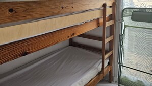 Un lit superposé avec une structure en bois et du linge de lit blanc.