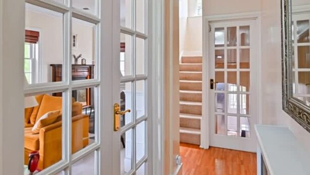 A hallway with a wooden floor, white doors, and a mirror on the wall. - Your Spacious South East Sanctuary | Fast City Links (London)