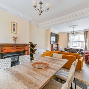 A dining area with a wooden table, cushioned chairs, and a sofa with patterned cushions.
