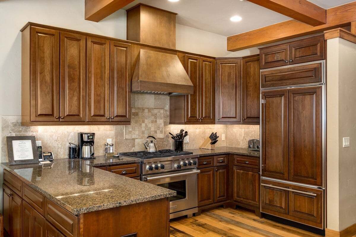 Una cocina con armarios de madera, encimera de granito, estufa y refrigerador.