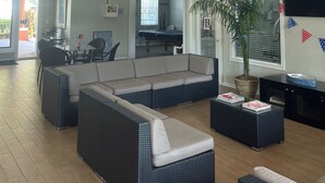 A spacious living room with a large sectional sofa, a ceiling fan, and a pool table.