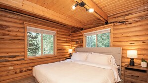 Une chambre dans une cabane en bois, avec un lit, deux lampes de chevet et une table de chevet.