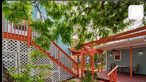 A back patio with a wooden deck, a white lattice fence, and a seating area with chairs and a table.