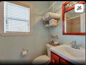 Une salle de bain avec des toilettes, un lavabo et une fenêtre équipée de stores.