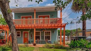 A two-story house with a balcony, a porch, and a well-maintained garden.