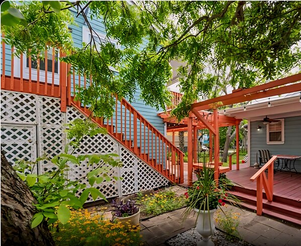 A back patio with a wooden deck, a white lattice fence, and a seating area with chairs and a table.