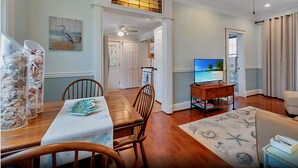 A spacious living room with a dining area, a TV, and a ceiling fan.