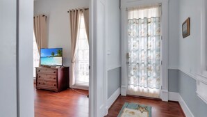 A room with a wooden dresser, a television displaying a beach scene, and a patterned rug.