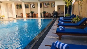 A swimming pool with lounge chairs and tables, surrounded by walls and potted plants. - The Ocean Pearl Hotel Negombo (Kochchikade)