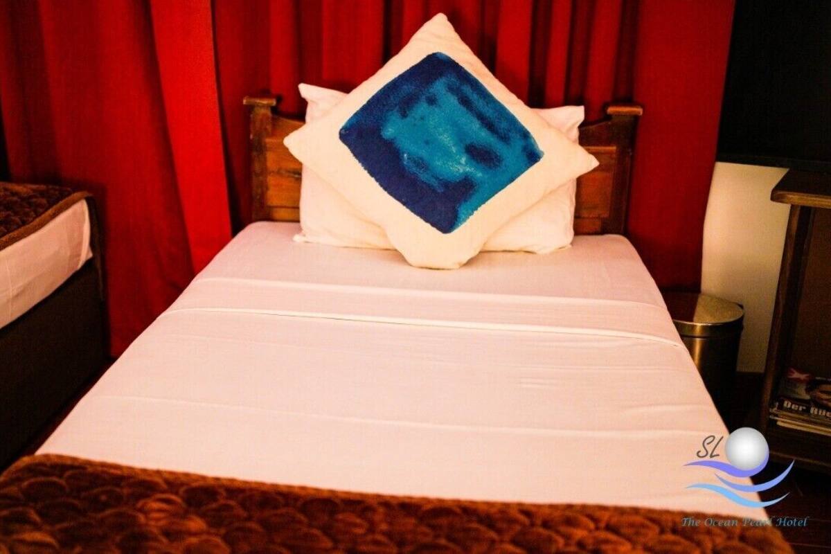 A hotel room with a bed, a nightstand, and a red curtain.