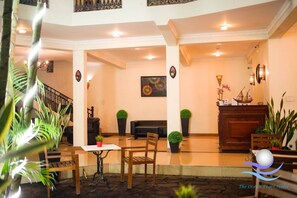 A lobby with a reception desk, seating area, and a staircase. - The Ocean Pearl Hotel Negombo (Kochchikade)