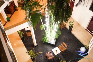 Un atrium interior con fuente central, rodeado de asientos de madera y plantas en macetas.