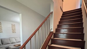 A staircase with wooden steps and a metal railing, leading to a landing with a sofa and a decorative wall piece. - Galactic Oasis Theme Home,  Marvelous 5-bedroom house with AC in Aurora, TV’s (Aurora)