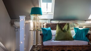 A cozy loft bedroom with a sloped ceiling, a wooden bench with cushions, a floor lamp, and a window with daylight. - The Cocktail Lounge - sleeps 2 guests  in 1 bedrooms (Nantwich)