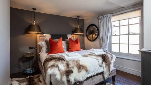 A bedroom with a large bed, two bedside lamps, a mirror, and a window with curtains. - The Cocktail Lounge - sleeps 2 guests  in 1 bedrooms (Nantwich)