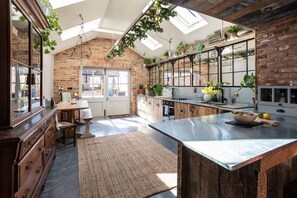 A kitchen with exposed brick walls, skylights, and wooden cabinetry.