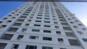 Un edificio alto con varios pisos, cada uno con balcones y unidades de aire acondicionado.