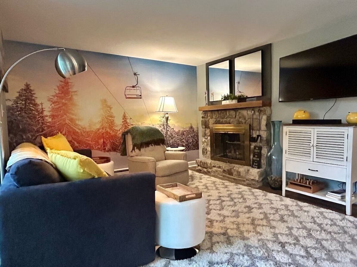 Un salon avec une cheminée, un canapé, une table basse et un téléviseur.