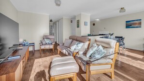 Een moderne woonkamer met leren banken, een houten salontafel en een eethoek met een tafel en stoelen.