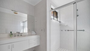 Een moderne badkamer met een douchecabine van glas, een witte wastafel met spiegel, en een vloer van hexagontegels.