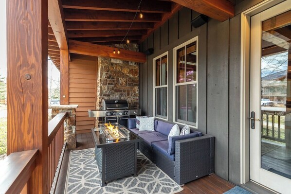 Un patio al aire libre con una chimenea de piedra, una parrilla y una zona de estar con un sofá y sillones.