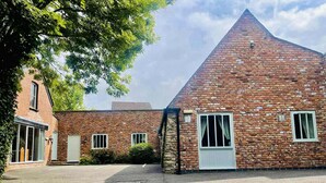 A brick building with a triangular roof, a door, and windows.