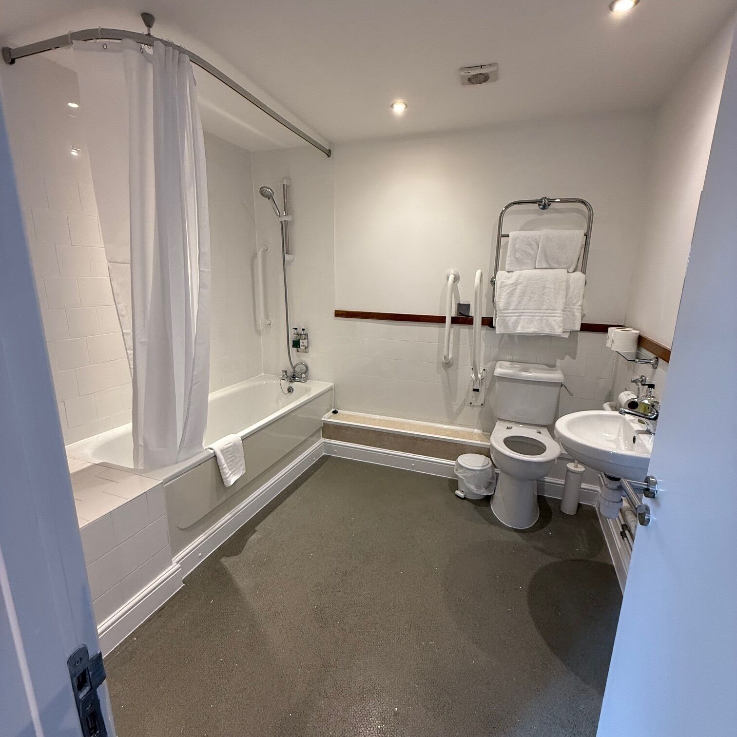 A modern bathroom with a bathtub, shower, toilet, and sink.