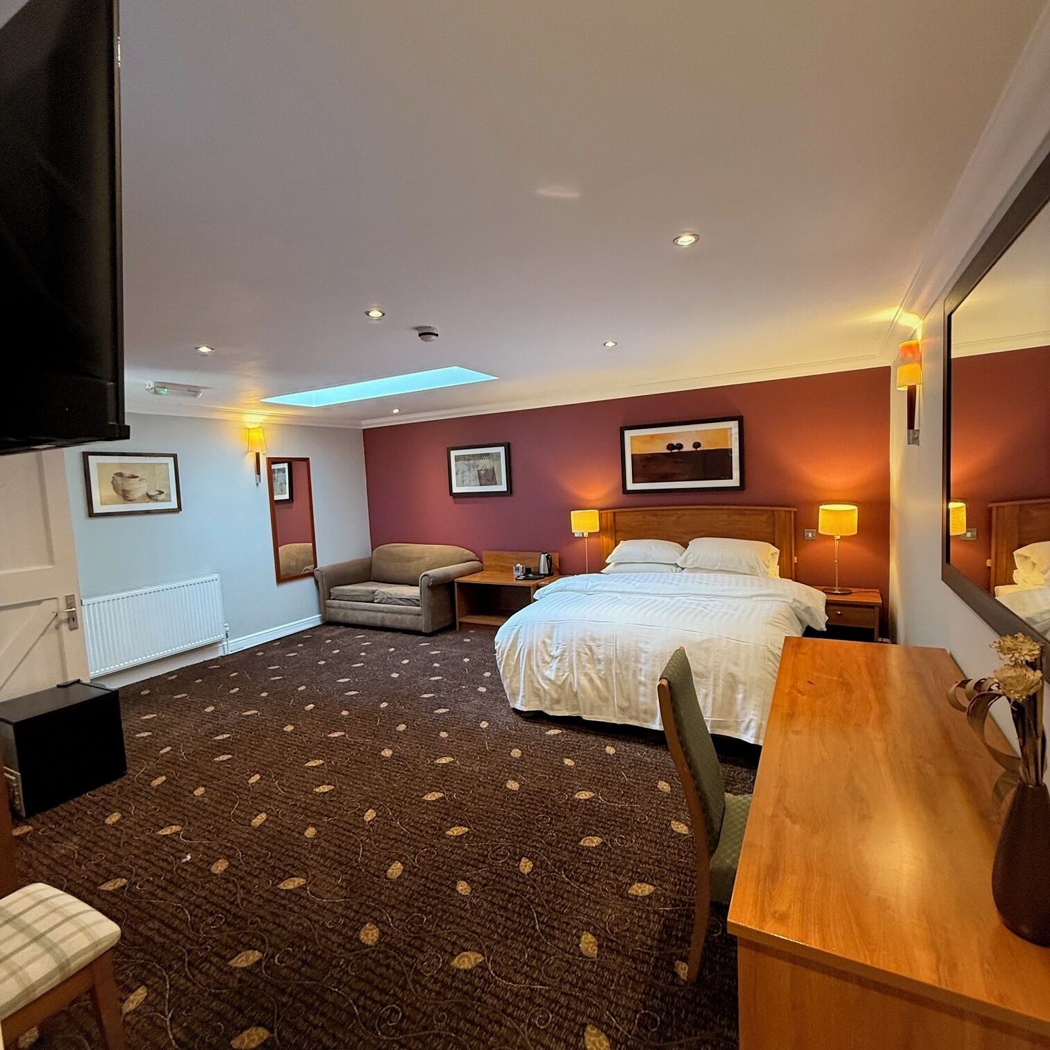 Ein Hotelzimmer mit einem Bett, einem Sessel, einem Schreibtisch und einem Fernseher.