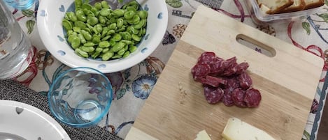 Et bord dækket med tallerkener, skåle, et skærebræt med ost og salamipølse, samt et brød.