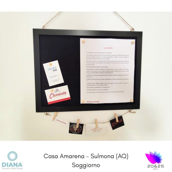 Un cartel enmarcado con texto y una tarjeta de presentación, colgado de un hilo con pinzas para la ropa.