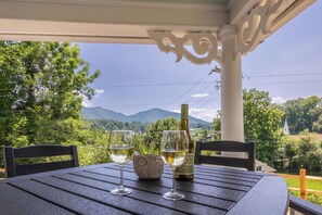 Une table avec deux verres à vin et une bouteille, le tout placé sur fond d’un paysage montagneux pittoresque.
