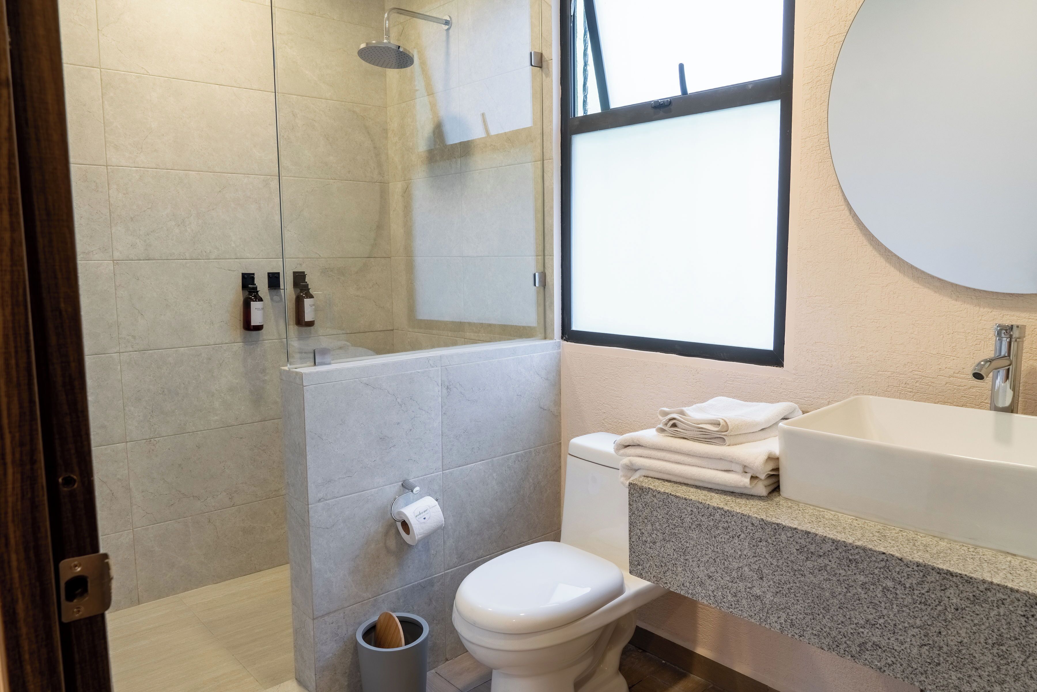 A modern bathroom with a shower, toilet, sink, and a large mirror.