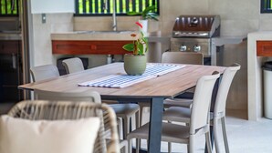 Une cuisine moderne avec un coin repas, comprenant une table avec des chaises, une plante en pot et un barbecue.