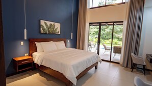 Une chambre avec un grand lit, une table de chevet, une chaise et une vue sur l’extérieur grâce à une porte-fenêtre coulissante.