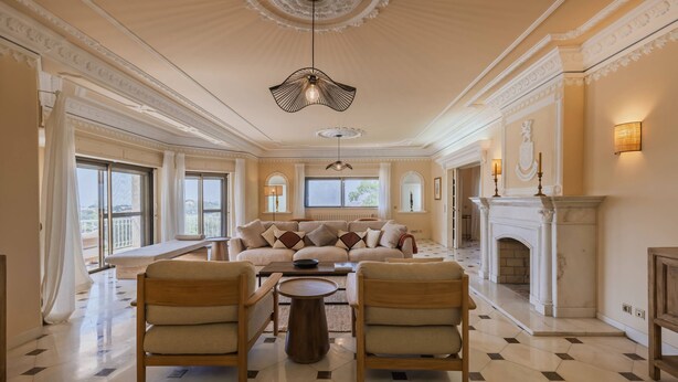 A spacious living room with a high ceiling, a fireplace, and a large window. - 184 - Ocean Views Golf Villa (Cascais)