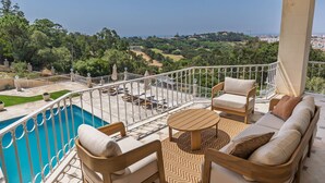 A balcony with a pool, outdoor furniture, and a view of the landscape. - 184 - Ocean Views Golf Villa (Cascais)