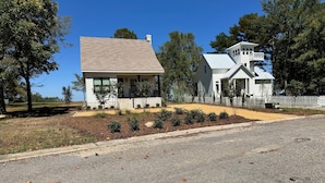 A two-story house with a front porch, a fenced yard, and a clear blue sky.
