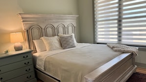 A bedroom with a bed, nightstand, and dresser.