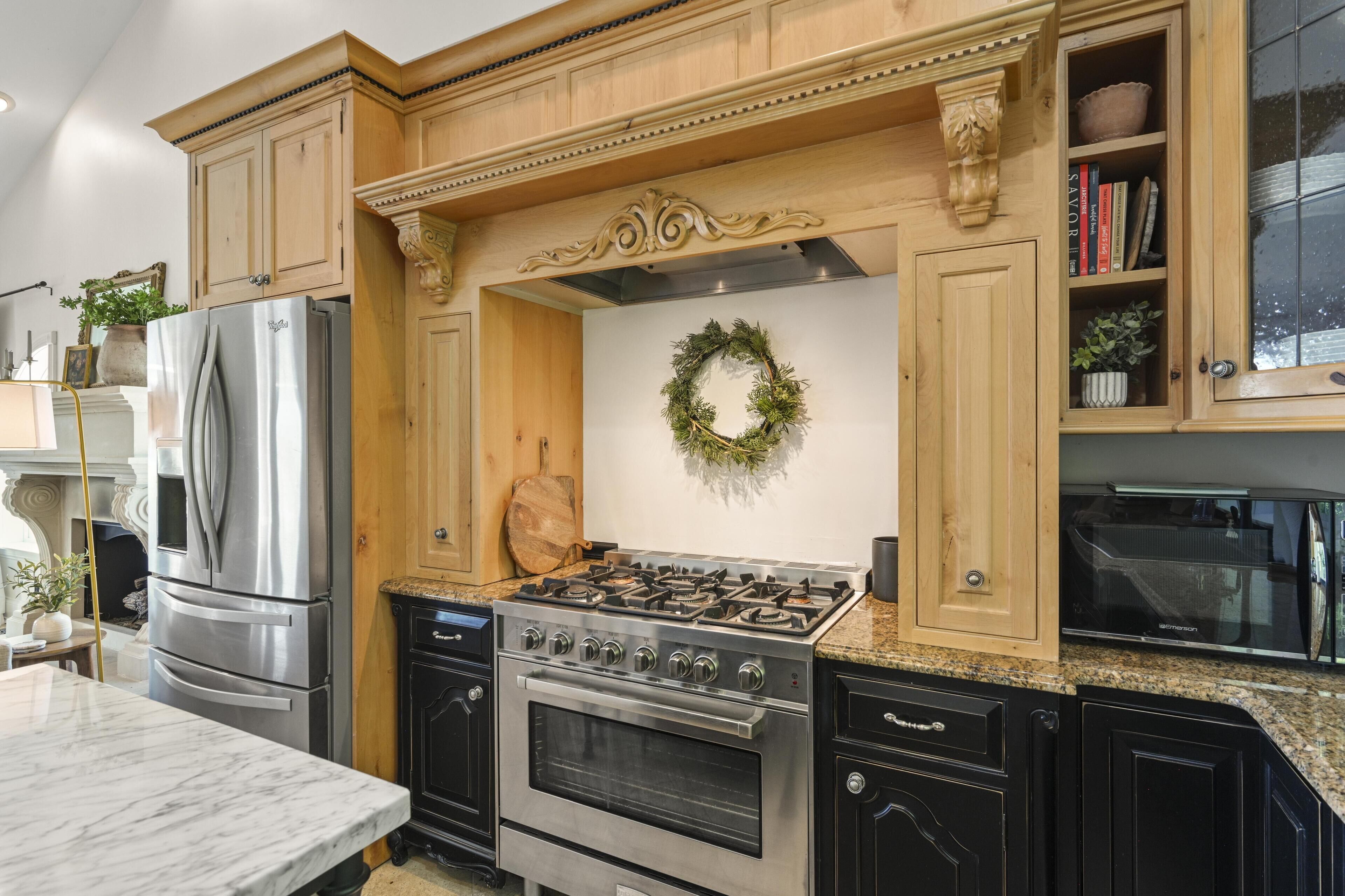 A kitchen with a stainless steel refrigerator, a gas stove, and wooden cabinetry.