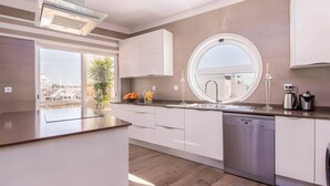 Ett modernt kök med diskmaskin, diskho och ett fönster med utsikt över stadsbilden.