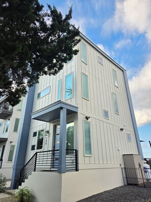 Un edificio de varios pisos con balcón, escaleras y entrada protegida por una reja.