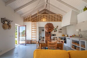 A spacious kitchen with a high ceiling, wooden ceiling beams, and a hanging light fixture. - Alentejo Rural Retreat w/lap pool (beach&country) (Santiago do Cacém)