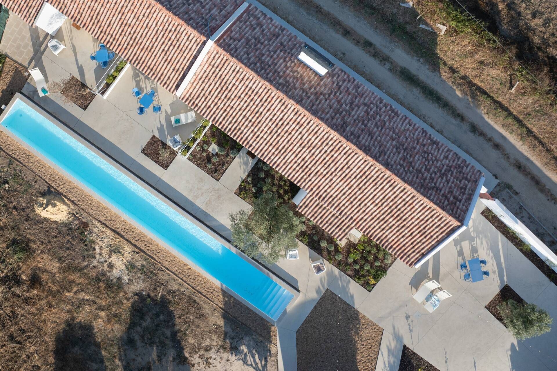 An aerial view of a property with a swimming pool, outdoor seating, and a tiled roof.
