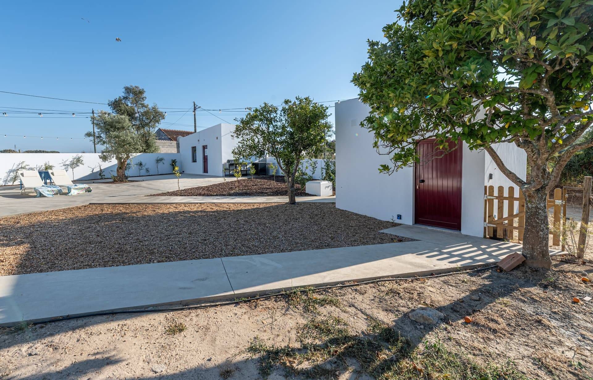 A residential area with white houses, a red door, and a tree.